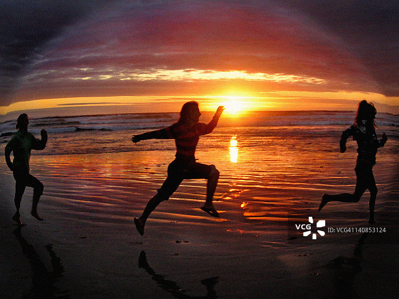 三个女人在日落时在海滩上跑步图片素材