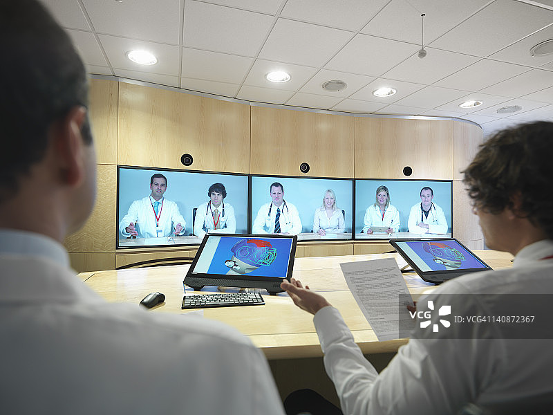 医疗专业人士在会议室通过屏幕进行视频会议图片素材