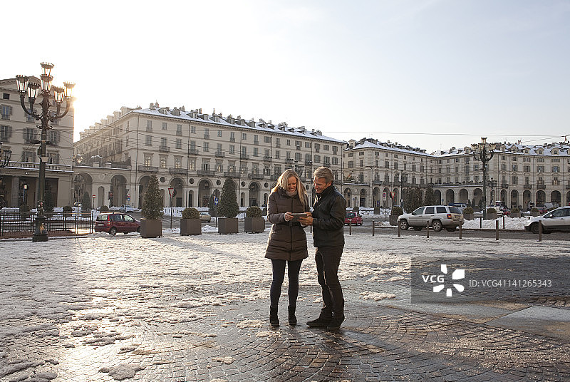情侣在城市广场上看平板电脑图片素材