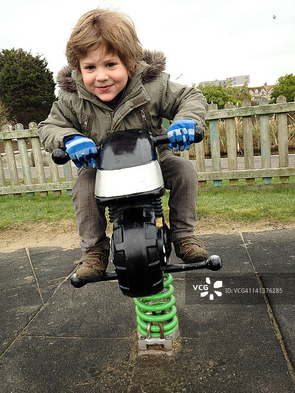 男孩在游乐场摩托车上玩耍图片素材