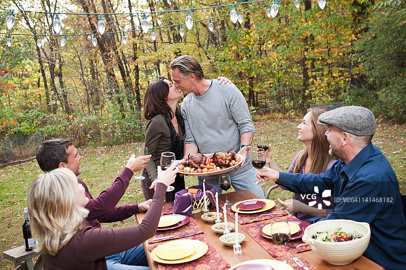情侣与朋友在户外晚餐时接吻图片素材