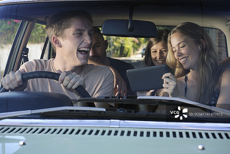 朋友们在车里看平板电脑并大笑图片素材