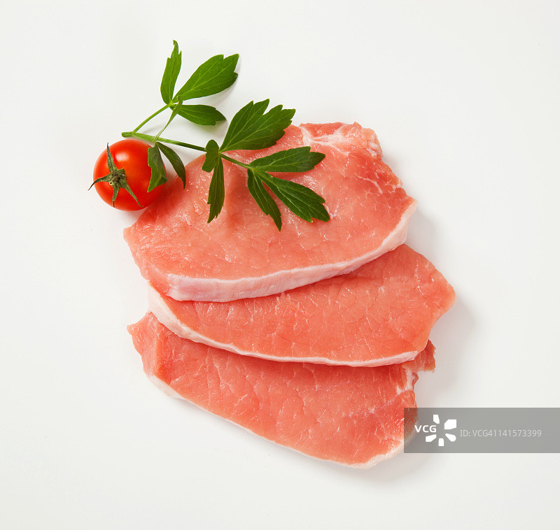三块生猪排、香蜂草、樱桃番茄，白色背景图片素材