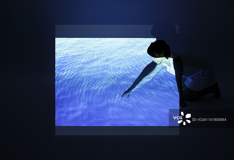 女人触摸蓝色海面图片素材