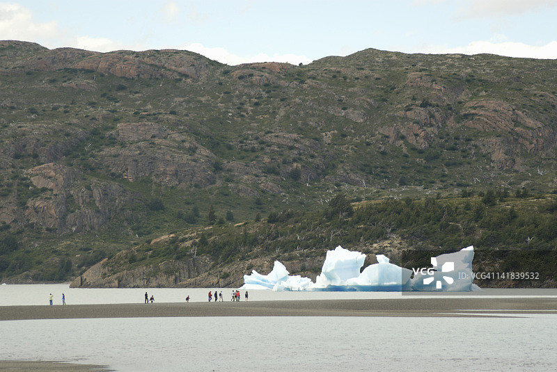 游客走在智利百内国家公园灰色湖的砂石坑中图片素材