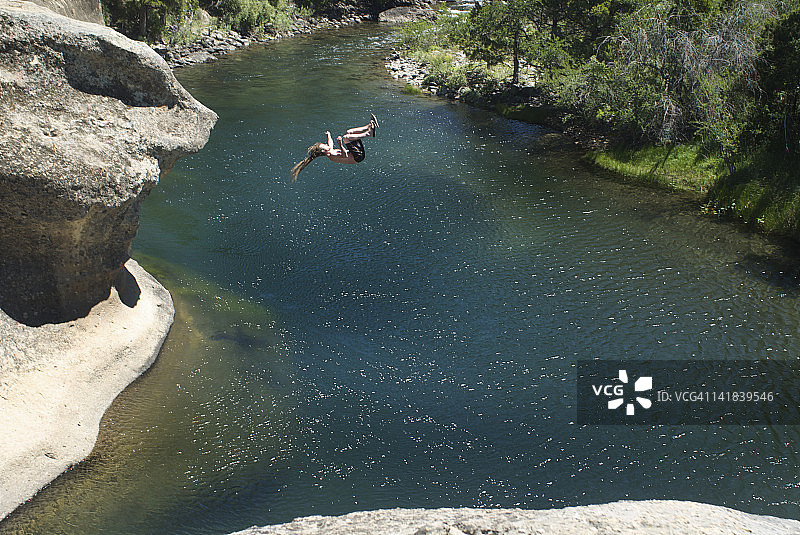 辫绳男子在阿根廷南部湖区从悬崖跳入河中图片素材
