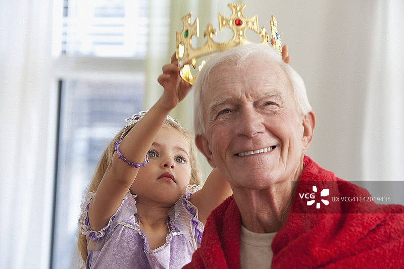 白人女孩给祖父戴王冠图片素材