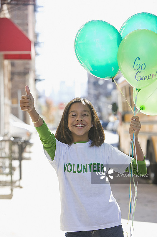 做志愿活动并拿着气球的西班牙裔女孩图片素材