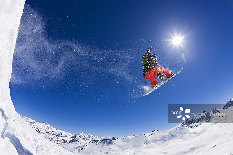 单板滑雪者飞跃雪山图片素材