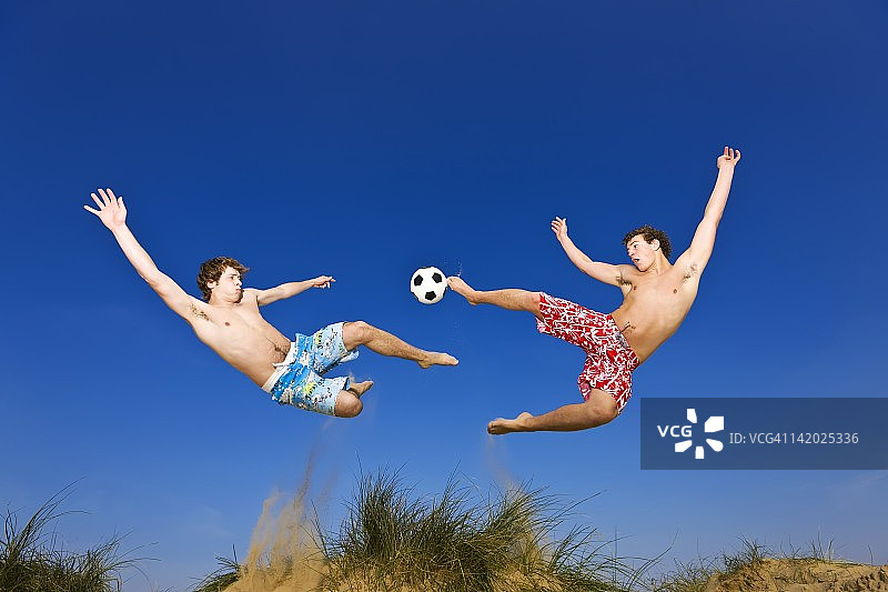两名球员在沙滩足球比赛中争夺球图片素材