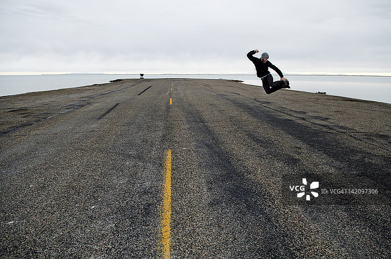 男人在道路尽头和犹他州邦纳维尔盐滩起点跳跃图片素材