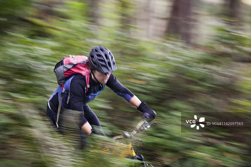 在单轨山地自行车道上蜿蜒前行的女人图片素材