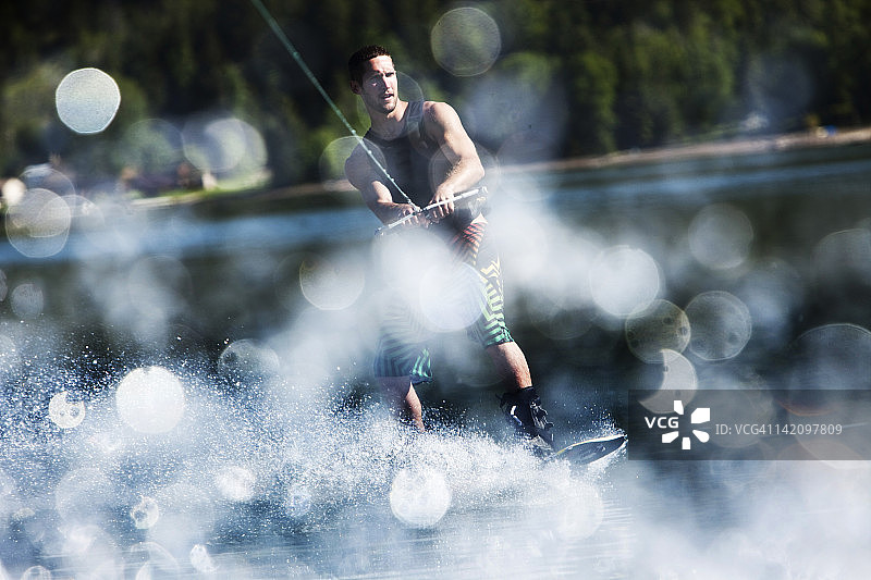 一个快乐的运动型男人在爱达荷州桑德point的阳光明媚的日子里玩尾波滑水。图片素材