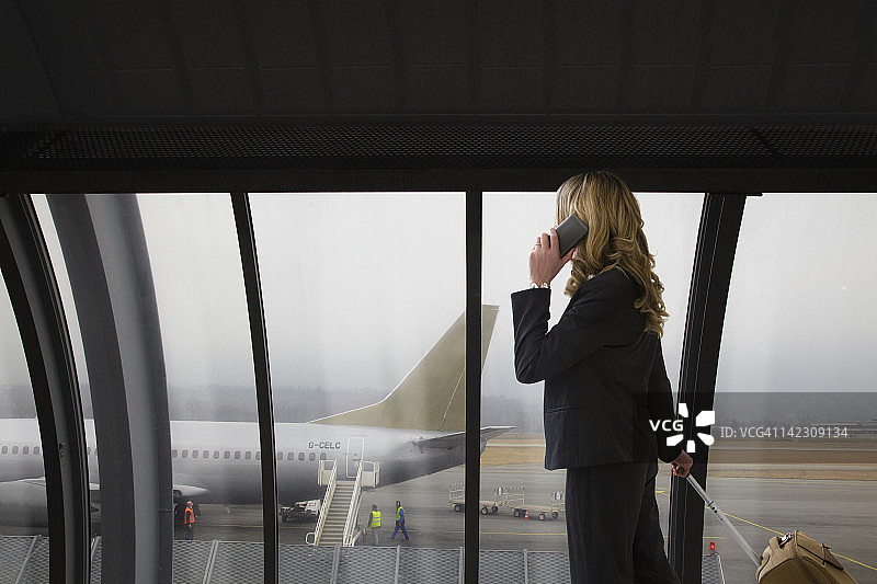 在机场航站楼使用手机的女商人图片素材