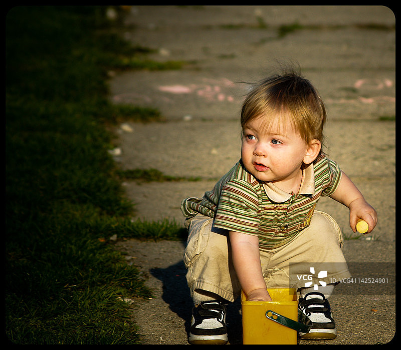男孩在人行道上用粉笔写作图片素材
