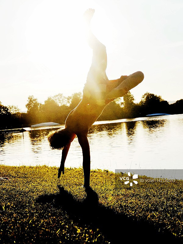 男孩在湖边做后空翻图片素材