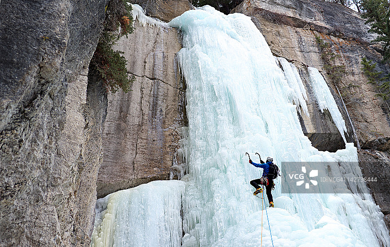 男子用冰镐攀登冰冻瀑布图片素材