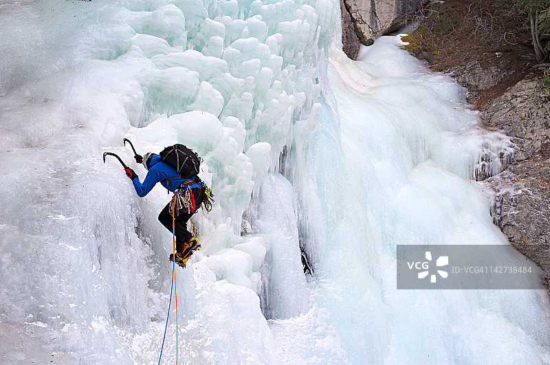 男子用冰镐攀登冰冻瀑布图片素材
