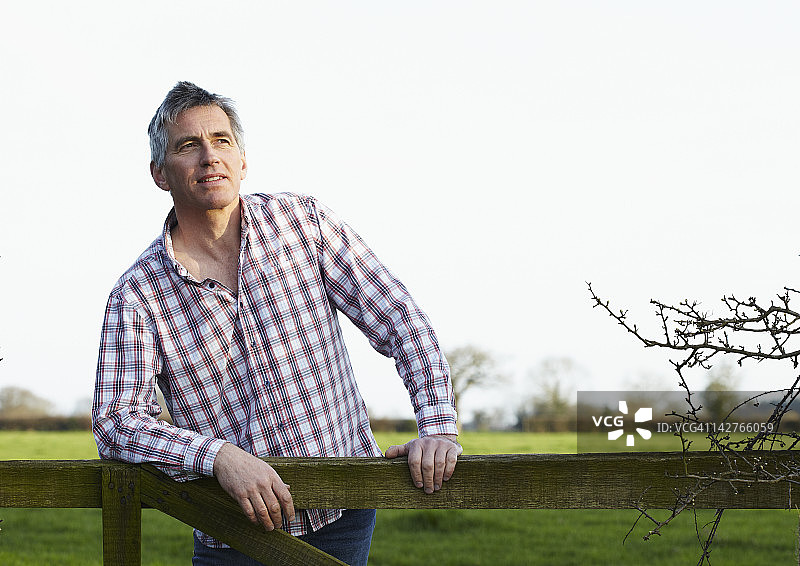 中年男人在乡下靠着大门图片素材