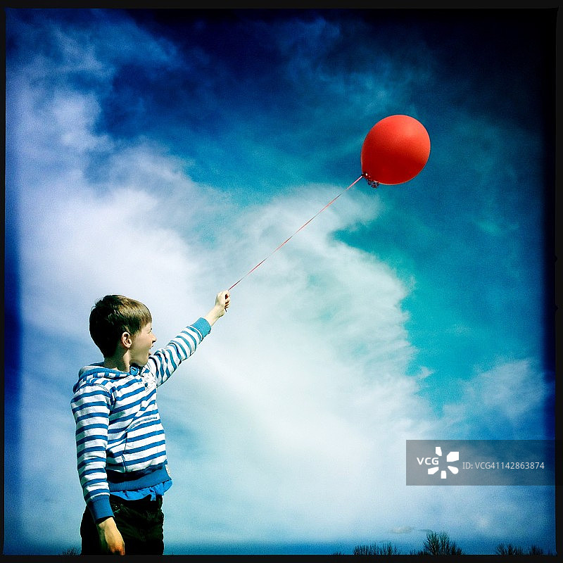 穿条纹衬衫的男孩拿着红色气球图片素材