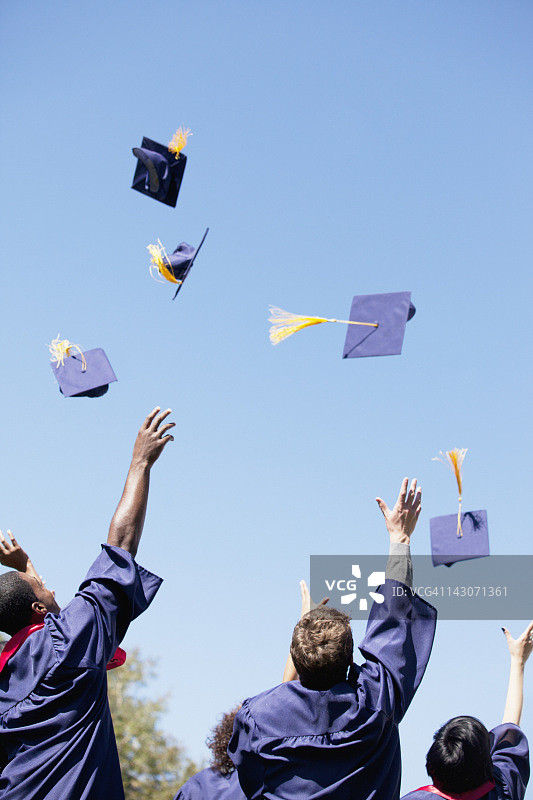 毕业生在户外将帽子抛向空中图片素材