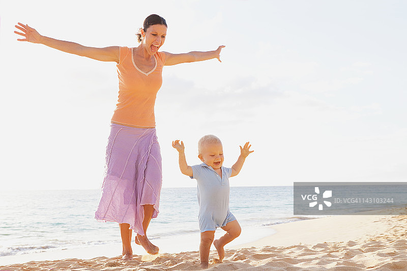 母亲和蹒跚学步的孩子在海滩图片素材