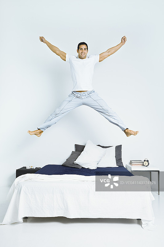 健康男人在床上跳跃图片素材