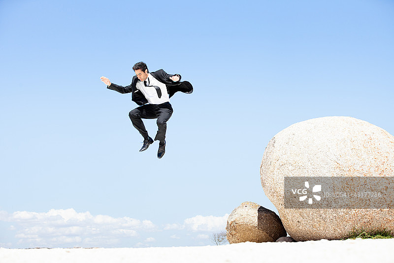 商人从巨石上跳下来图片素材