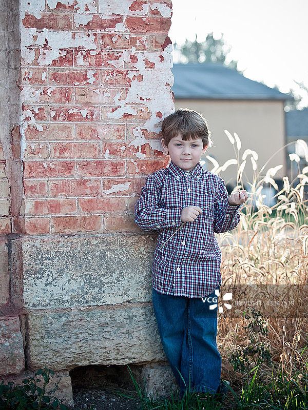 靠在砖墙上的男孩图片素材