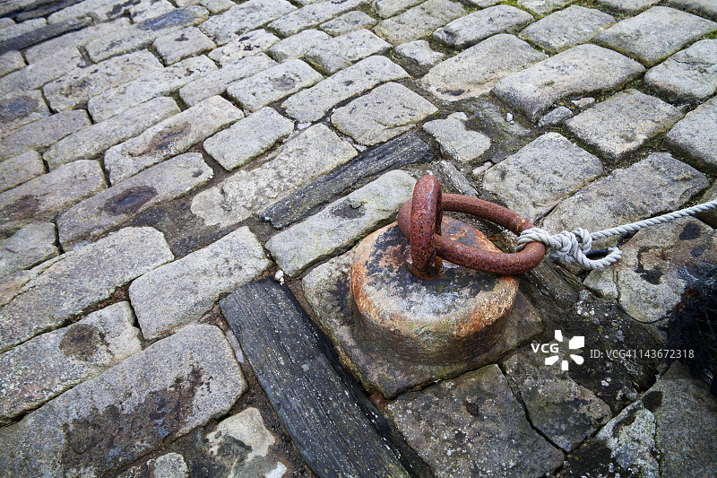 生锈的系缆柱、铁环和鹅卵石图片素材
