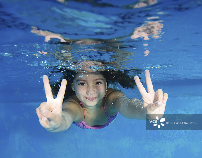 微笑的女孩在游泳池里玩耍图片素材