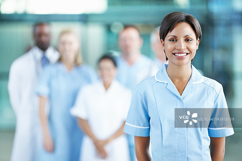 女医生微笑，背景有医疗团队图片素材