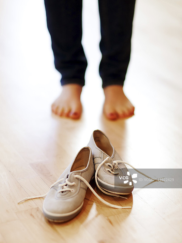 赤脚站在帆布鞋前的女人图片素材