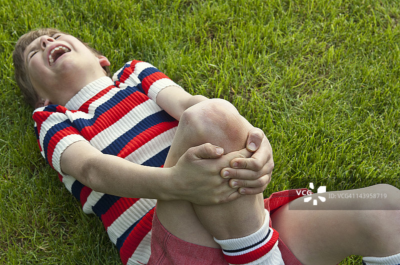 事故后痛苦地抓住腿的男孩图片素材