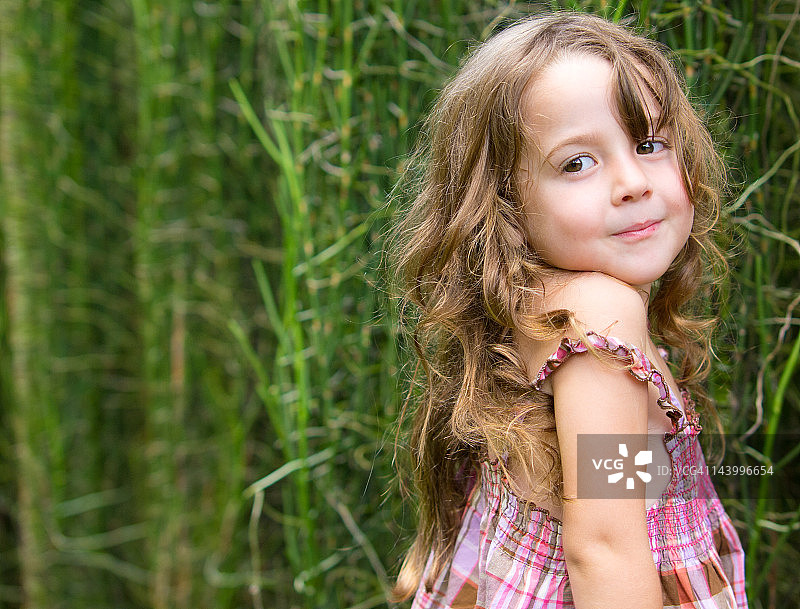 年轻女孩在灌木丛前摆姿势图片素材