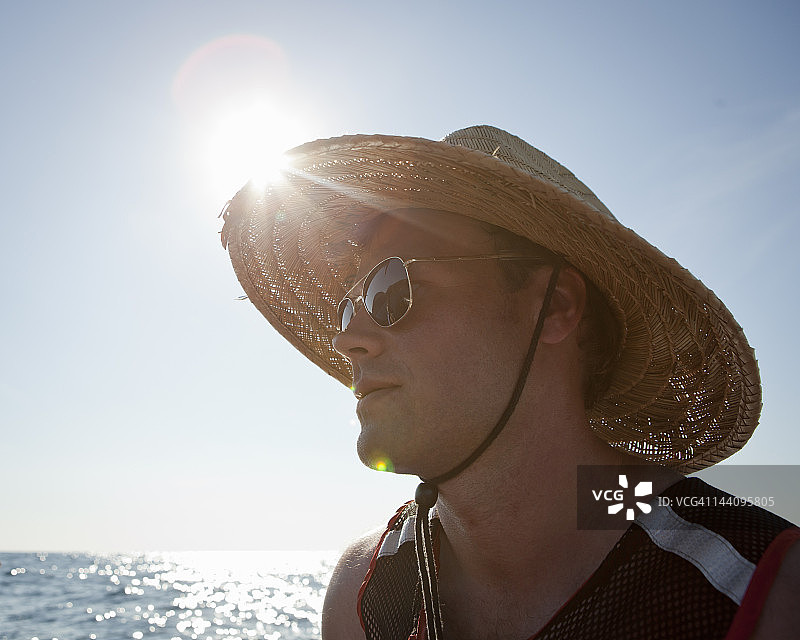 戴着帽子和太阳镜的男人在海上图片素材