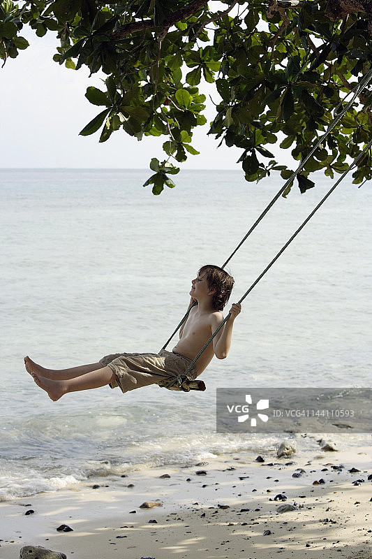 男孩在海边荡秋千图片素材