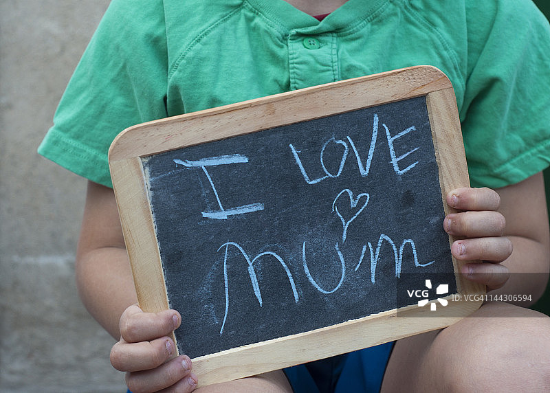 男孩拿着写有“我爱妈妈”的石板图片素材