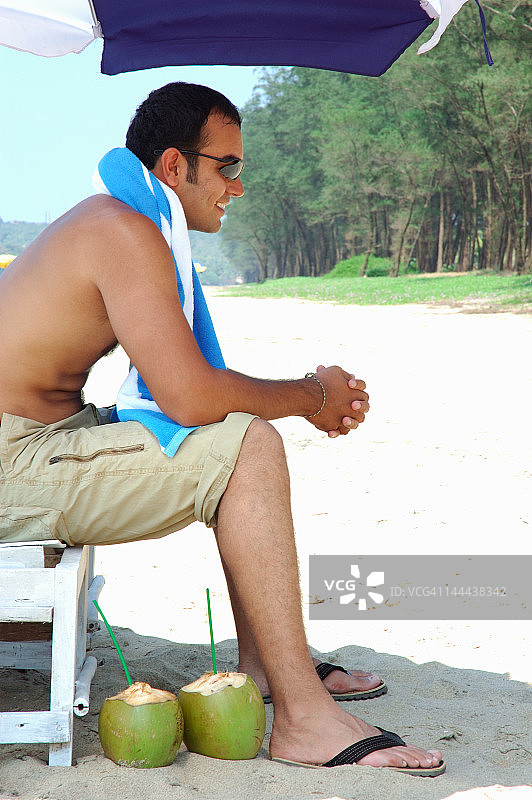 坐在沙滩伞下的年轻男人图片素材