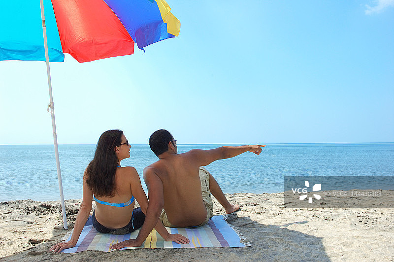坐在海滩上的一对夫妇的背影图片素材
