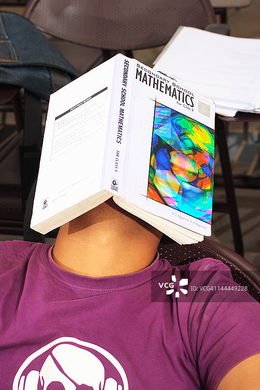 男孩用书遮脸特写图片素材