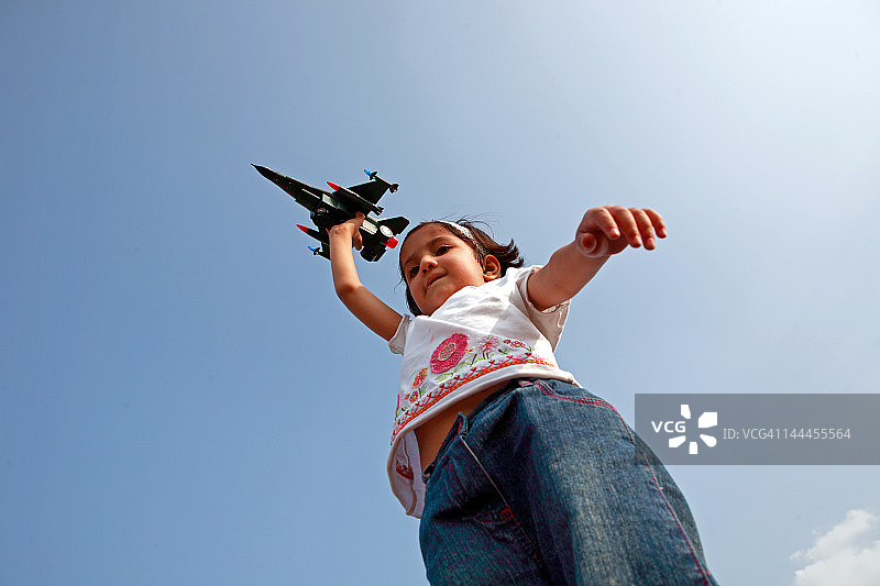 拿着玩具战斗机的女孩仰视角度图片素材