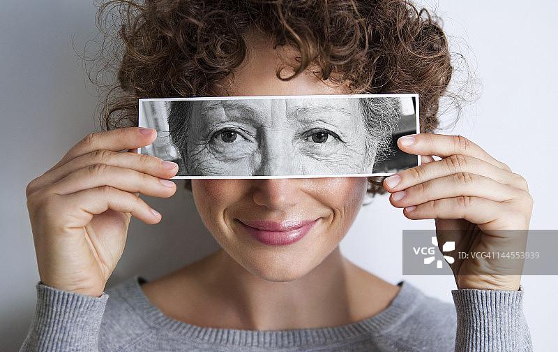 拿着老年妇女眼睛照片的女人图片素材