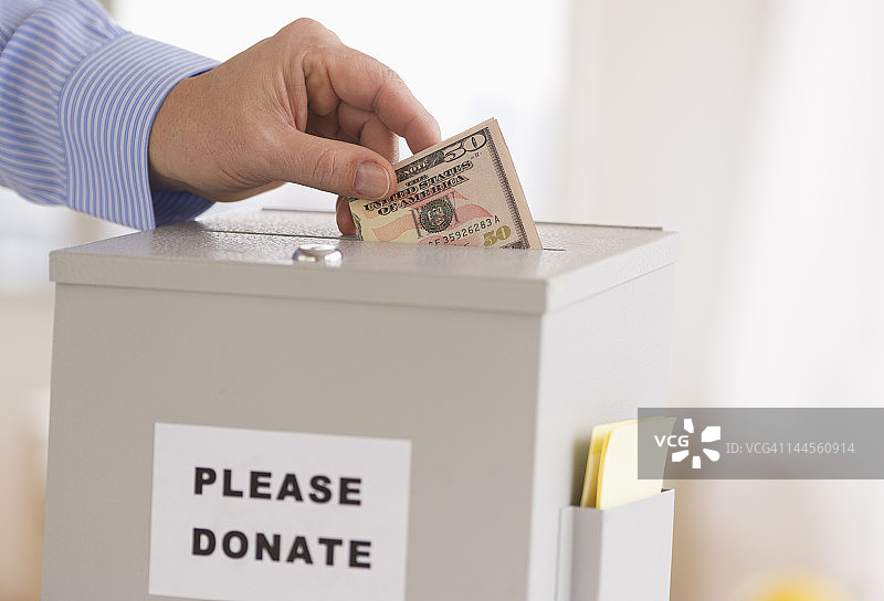 新泽西州泽西市，男子将美元放入捐款箱图片素材