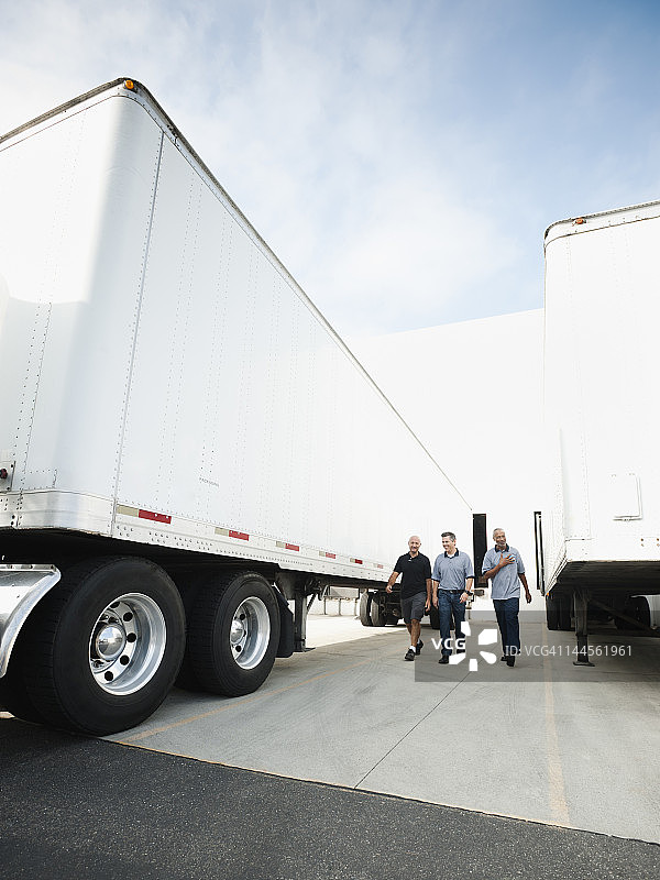 美国加利福尼亚州圣安娜，三个男人在卡车之间行走图片素材
