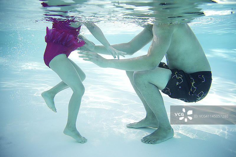 年轻女孩和父亲或哥哥在游泳池里玩耍图片素材