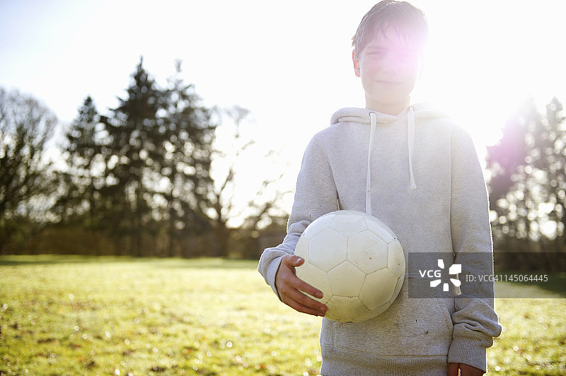 男孩在草地上抱着足球图片素材