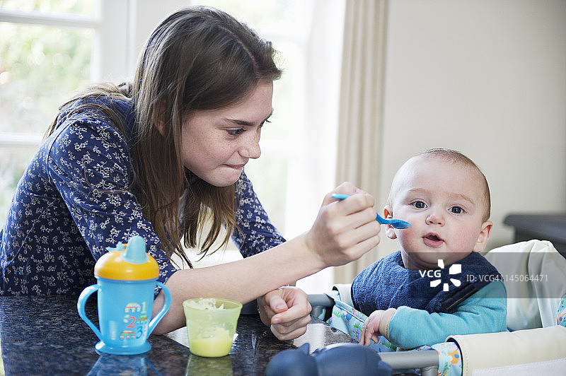 女孩在餐桌旁喂弟弟图片素材