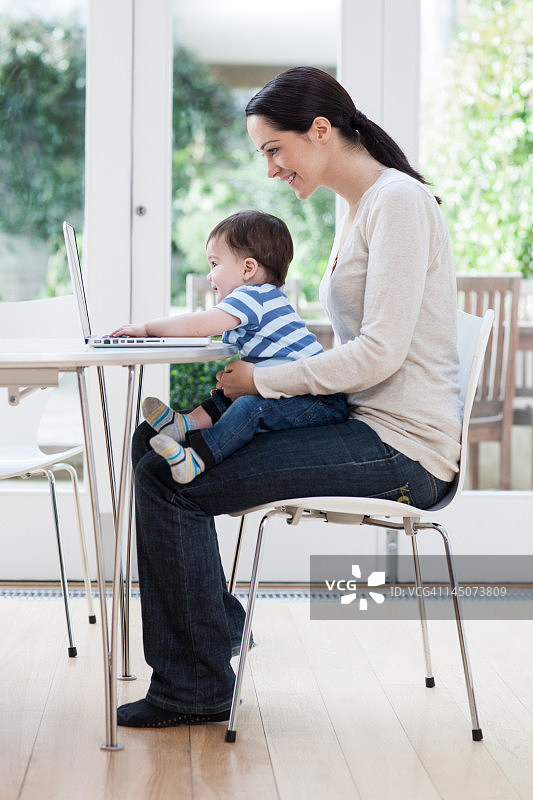 年轻女子与男婴使用笔记本电脑图片素材
