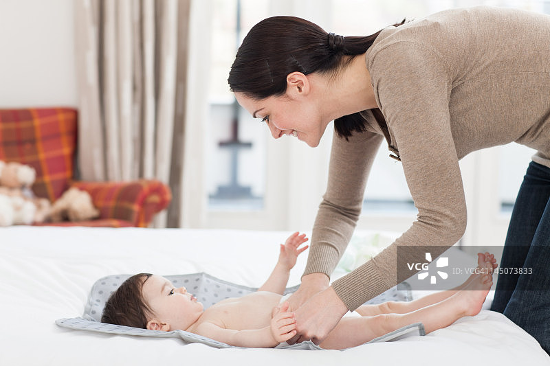 年轻女人给宝宝换尿布图片素材